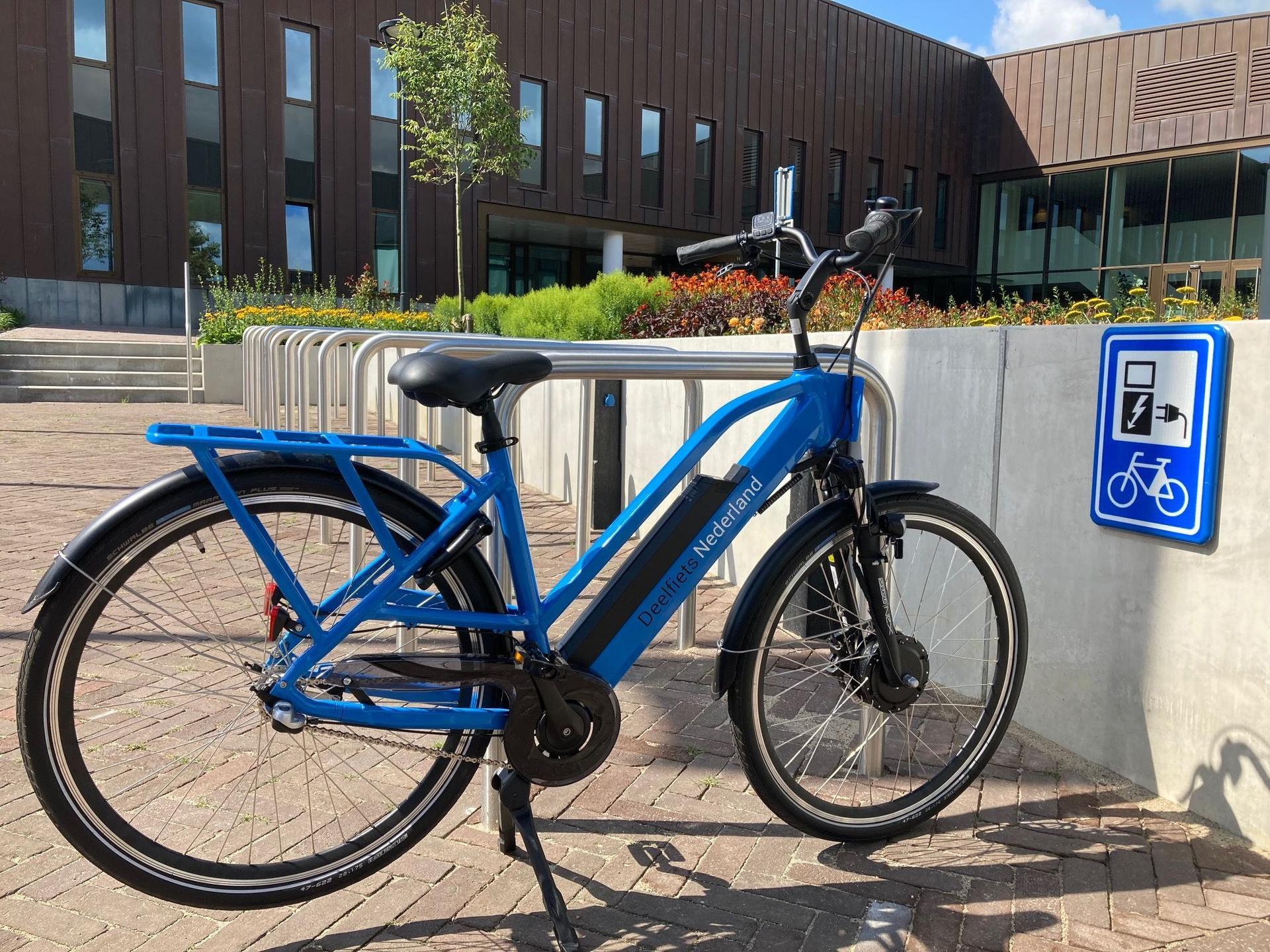 Een elektrische deelfiets aan het opladen bij een elektrische droppointlocatie van Deelfiets Nederland