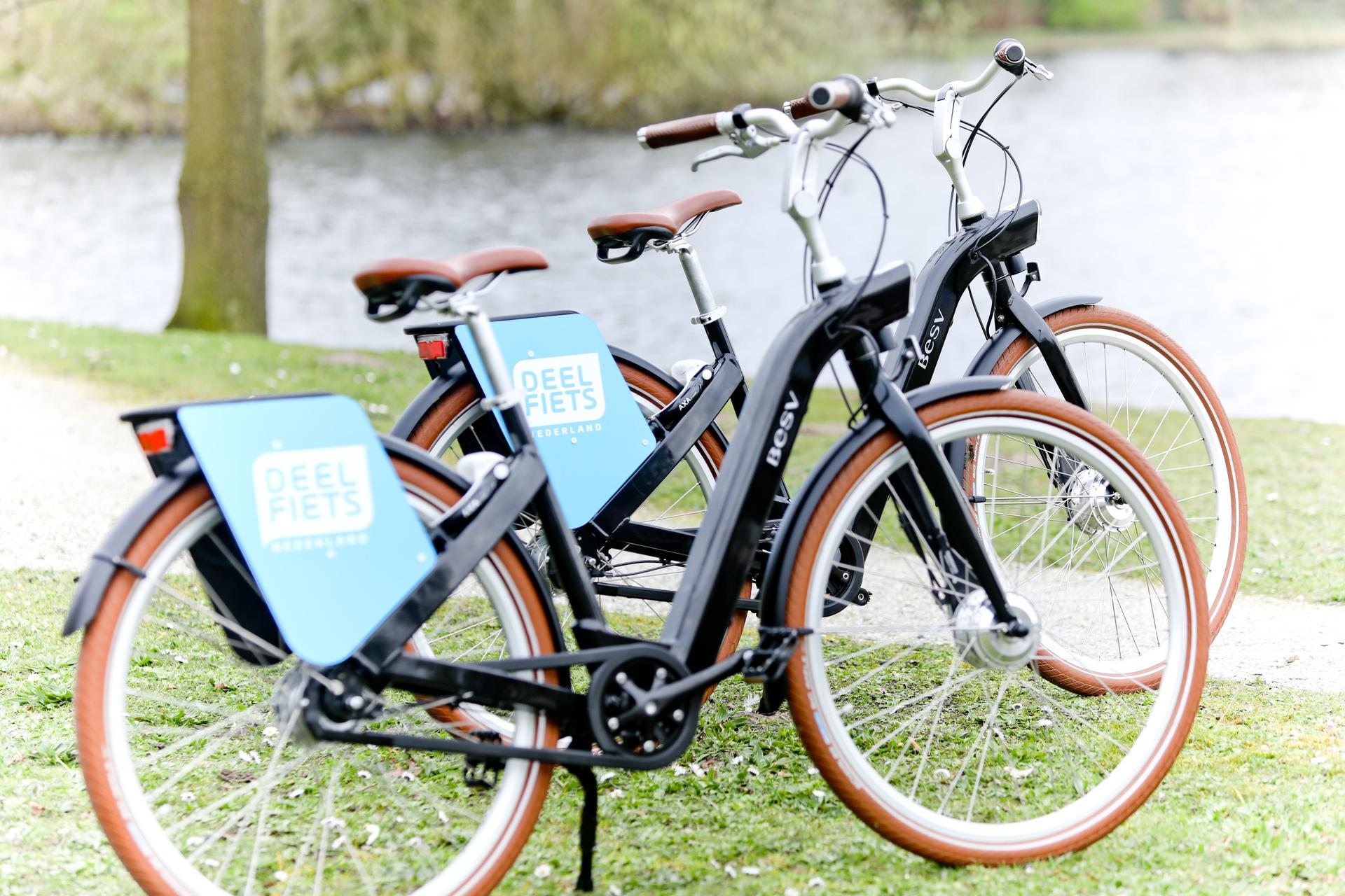 Twee deelfietsen van Deelfiets Nederland naast het water.