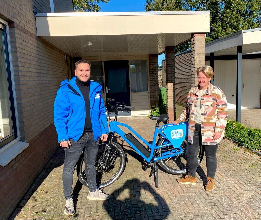 Een lid van het team van Deelfiets Nederland bij de trotse winnaar van de P+R Hoogkerk winactie